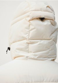 Doudoune blanche crémeuse, dotée d'un design matelassé, d'une capuche et d'accents en cordon noir pour l'ajustabilité. Fini lisse avec une texture douce.