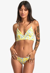 Completo bikini floreale giallo e blu con una texture a coste. Il top presenta un collo a V e spalline sottili; il pantalone ha un taglio a vita bassa.