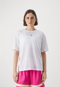 Hvit T-skjorte med korte ermer laget av lett stoff, med en svart Jordan-logo og en liten Nike-svisj over.