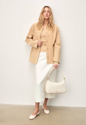 Béžová oversized bunda s veľkými gombíkmi, béžový priliehavý top, biela sukňa, svetlobéžová kabelka so zlatými kovaniami a zladené svetlobéžové baleríny.