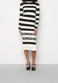 Musta-valkea raitapaita, jossa on pitkät hihat, röyhelöhelma ja "LOVE" -painatus alaosassa.