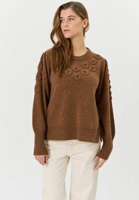 Brauner gestrickter Pullover mit strukturierten floralen Akzenten auf den Schultern, geripptem Saum und Bündchen. Weicher, gemütlicher Stoff mit lockerer Passform.