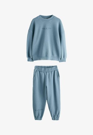 Jasnoniebieska polarowa bluza i dopasowane spodnie dresowe z elastycznymi mankietami oraz napisem "BAKER" na obu elementach.