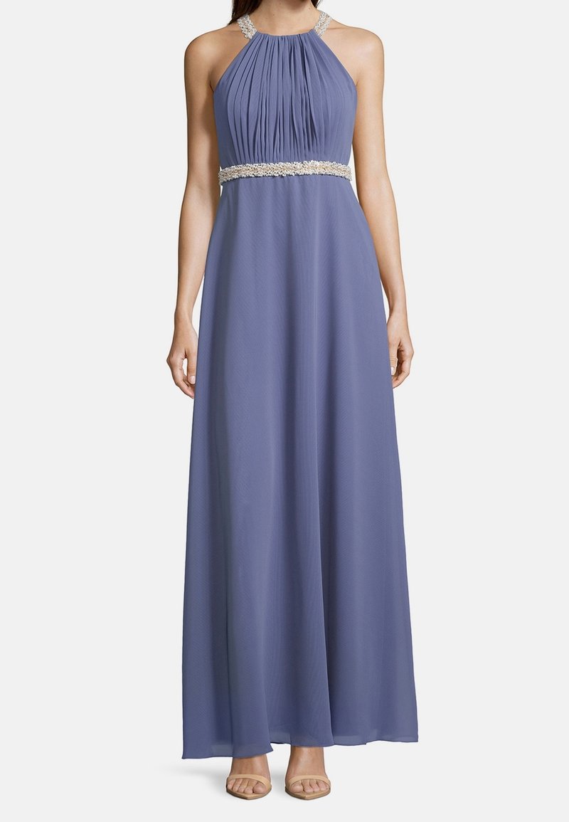 Robe longue lavande sans manches à col halter plissé avec des embellissements perlés sur les bretelles et la taille, portée avec des talons ouverts couleur nude.