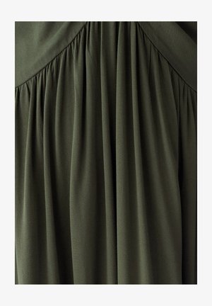 Tissu vert olive foncé avec des plis froncés et un détail de couture en forme de chevron près du centre supérieur.