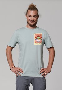 T-shirt à manches courtes vert menthe avec un motif de glace coloré sur le devant. Matière en coton lisse avec un design à col rond.