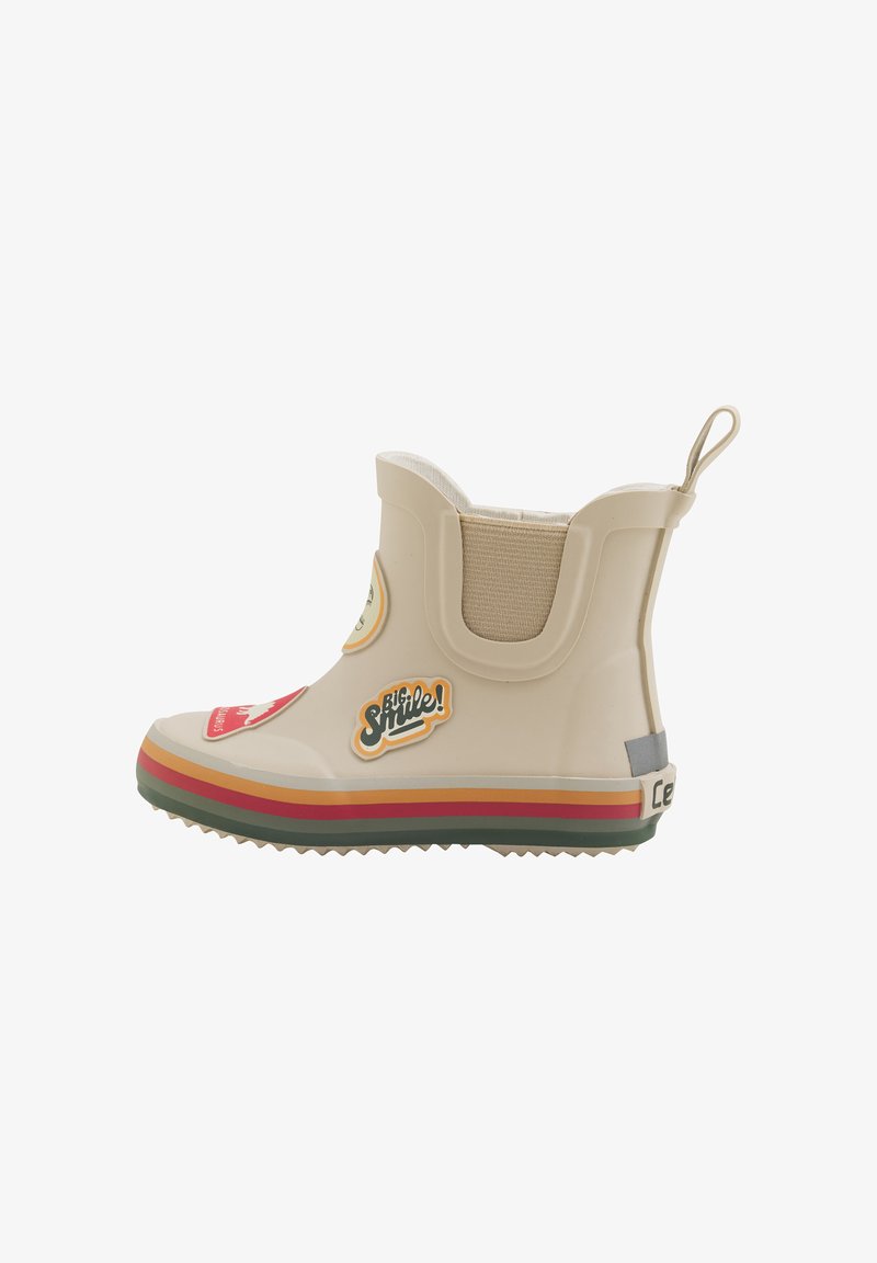 Beige rubberen enkellaars met elastische zijpanelen, kleurrijke gestreepte zool en decoratieve stickers, waaronder "Grote Lach!" en grafische afbeeldingen.