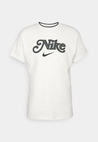 Vit kortärmad t-shirt i bomull med en framträdande svart och grå broderad "Nike"-logotyp på framsidan, rund hals med svart trim.