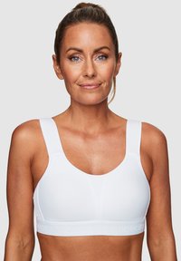 Vit sportbh med tjocka axelremmar, rundad nacke och en texturerad rem som har varumärkesnamnet. Slätt tyg med minimala sömmar.