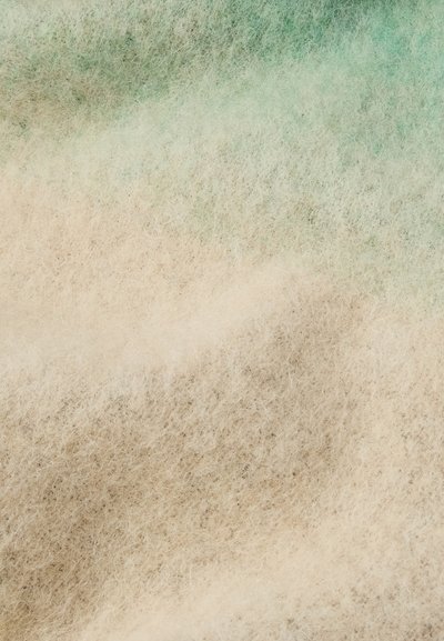 Τσόχα σε κρέμα και ανοιχτό πράσινο, με λεπτό, fuzzy υφή και απαλές χρωματικές διακυμάνσεις σε γήινες αποχρώσεις.