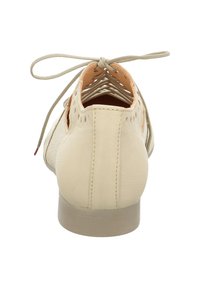 Beige leather shoe with a low heel, featuring a lace-up design and cutout detailing on the sides for ventilation. Smooth texture.