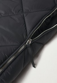 Černá péřová bunda se čtvercovým prošíváním, metalový zip s textilním táhlem a hladkým, lesklým povrchem.