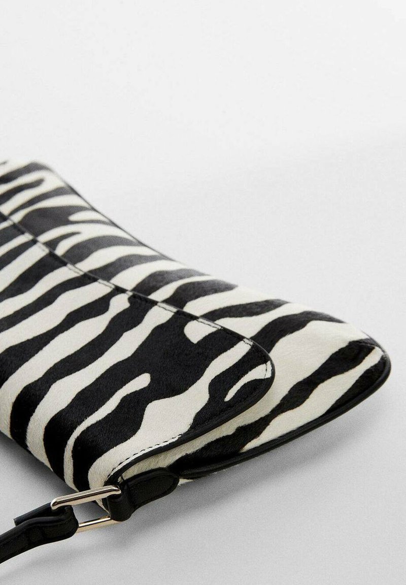 Clutch a stampa zebra con superficie testurizzata bianca e nera e finitura liscia, accentuata da una tracolla nera e accessori in argento.