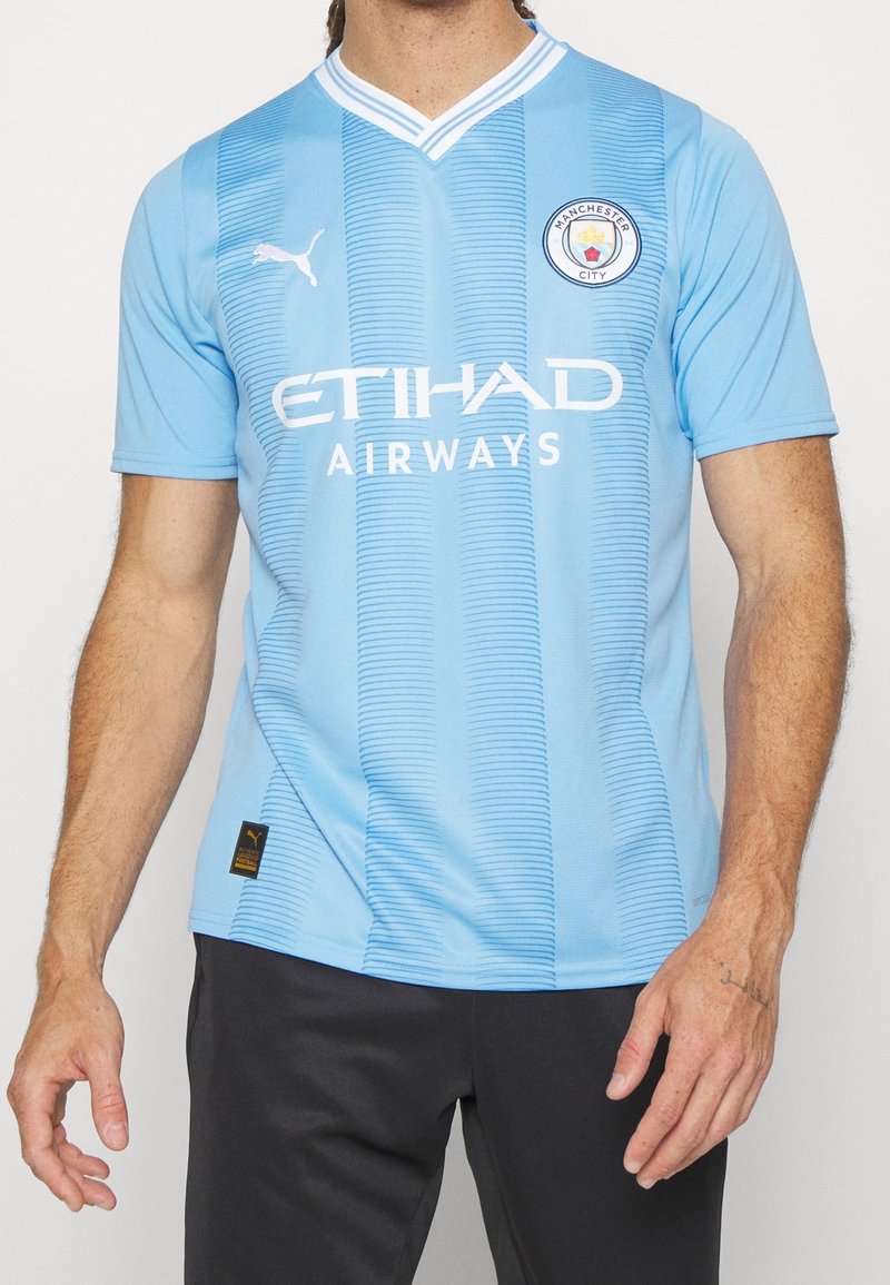 Maglia da calcio azzurro chiaro con strisce verticali, colletto bianco e logo. "ETIHAD AIRWAYS" stampato in bianco sul petto.