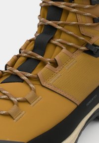 Rudos spalvos vandeniui atsparūs žygio batai su tekstūruotu viršumi, juodais akcentais ir šviesiai rudomis raištelėmis. Batų priekyje sustiprintas dėvėjimui atsparus apsauginis kraštas ir minkštas kulnas.