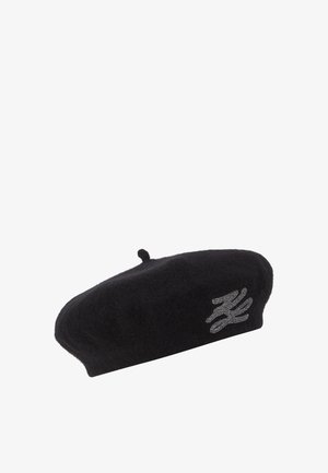 Beret de lana negra con una textura suave, que presenta un acento de diseño gráfico plateado. Forma redondeada con una pequeña lengüeta en la parte superior.