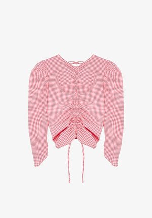 Blouse à manches longues en gingham rouge et blanc avec devant froncé et détails noués au niveau de l'encolure et de l'ourlet.