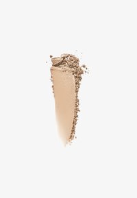 Polvere beige con una texture liscia, parzialmente stratificata, affiancata a particelle scure e sciolte. Il prodotto ha una finitura opaca e bordi senza soluzione di continuità.