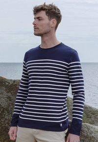 Navy og hvid stribet langærmet skjorte lavet af blødt stof, med en rund halsudskæring og en lille logoaccent ved kanten.
