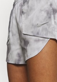 Nike shorts dengan pola tie-dye abu-abu dan putih, dilengkapi dengan pinggang elastis dan logo perak kecil di panel samping.