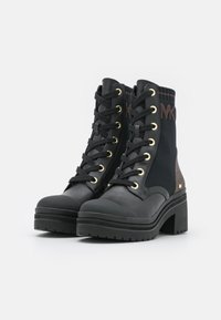 Bottines noires à lacets avec une semelle épaisse, œillets dorés et un mélange de cuir et de tissu. Présente un détail de logo sur le côté.