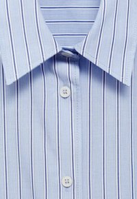 Chemise bleu clair avec fines rayures verticales bleu foncé, dotée d'un col classique et d'une patte de boutonnage sur le devant. Texture de tissu douce.