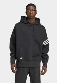 Sudadera negra con un bolsillo frontal, capucha con cuerda y tres rayas blancas en la manga izquierda. Presenta un pequeño logo blanco en el dobladillo.