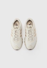 Scarpe sportive bianche e beige con tomaia in mesh, tre strisce diagonali, lacci rotondi e suola in gomma strutturata.