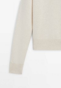 Manche longue de pull en laine couleur crème avec détails en côtes aux poignets et à l'ourlet sur fond blanc.