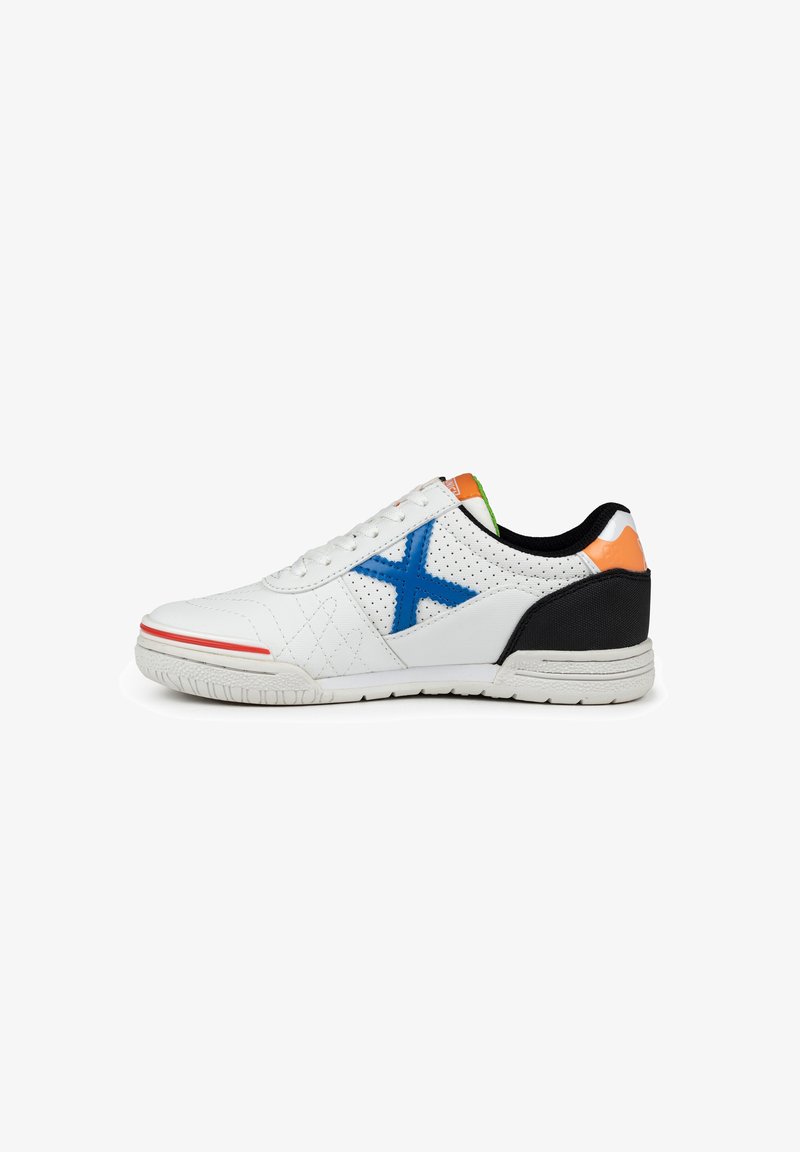 Zapatilla blanca con diseño de X azul, textura perforada, acentos en naranja y verde, tacón negro y franja roja en la suela.