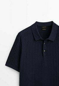 Polo bleu marine à manches courtes avec motif tricoté vertical texturé et patte de boutonnage à trois boutons.