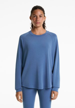 Sweat-shirt bleu à manches longues en tissu doux, avec des manches raglan et un col arrondi. Accompagné de leggings bleus assortis.