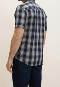 Korte mouwen geruit overhemd in marineblauw, wit en rode tinten, met een ruitenpatroon, een rugpas en een afgeronde zoom. Gekocht met donkere jeans.