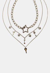Slojeviti srebrni ogrlice s velikim privjeskom u obliku zvijezde, malim privjescima u obliku ključa i srca; različiti stilovi lanaca i tekstura.