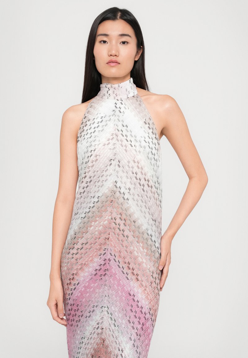 Robe à encolure halter présentant un motif en chevrons dans des teintes roses douces et blanches, avec un tissu texturé et fluide et une silhouette ajustée.