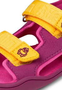 Sandali colorati con una superficie vellutata fucsia, cinturini gialli regolabili con texture stampata e un piccolo design di uccellino sul cinturino.
