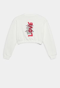 Sudadera blanca corta con mangas largas, que presenta texto negro y un diseño de mano roja en la parte posterior, mostrando varias palabras positivas.