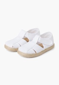 White canvas shoes with cut-out design, elastic strap, and espadrille-style braided jute sole. Smooth texture and lightweight construction.