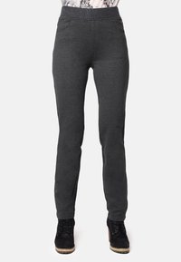 Pantalones de chándal grises con una textura suave, que presentan una cinturilla alta, bolsillos laterales y un diseño ajustado. Incluye un par de botas negras tipo tobillo.