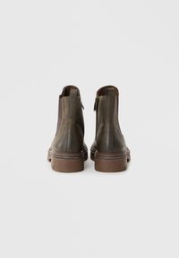 Brown leather ankle boots with a smooth finish, side zippers, and a layered rubber sole. Simple design with minimal accent detailing.