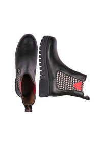 Stivaletti in pelle nera con suole chunky, lati a motivo houndstooth, dettagli rossi e linguette per facilitare la calzata e la rimozione.