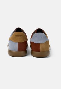 Suede sneakers with a mix of blue, brown, and tan colors. Features a rounded shape, soft texture, and "Camper" logo on the heel.