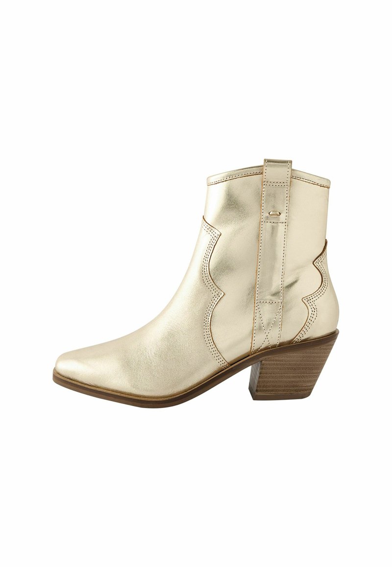Bota de tobillo de cuero dorado con punta afilada, diseño con ondas y tacón apilado. Presenta costuras y una pestaña en la parte trasera.