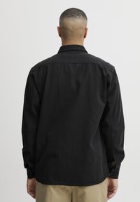 Zwarte langemouwen shirt van katoen, met een rechte zoom, met knoopmanchetten en een klassieke kraag. Verkrijgbaar in meerdere maten.