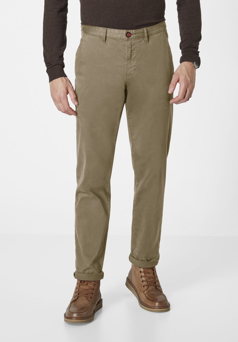 Khaki chinos with a straight fit, featuring a button closure and belt loops. Material has a smooth texture; paired with brown lace-up boots.