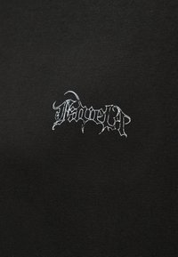 Μαύρο ύφασμα με μικρό, λευκό, περίπλοκο γοτθικό λογότυπο με κείμενο στο κέντρο της επιφάνειας.