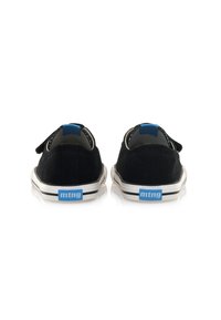 Zapatillas de lona negras con cinta de velcro, suelas de goma blancas y un acento azul en el talón. Presentan costuras en contraste y un logo.