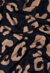 Stof med leopardmønster har mørk navy og beige farver. Teksturen ser blød og luksuriøs ud, med en krøllet, lagdelt overflade.