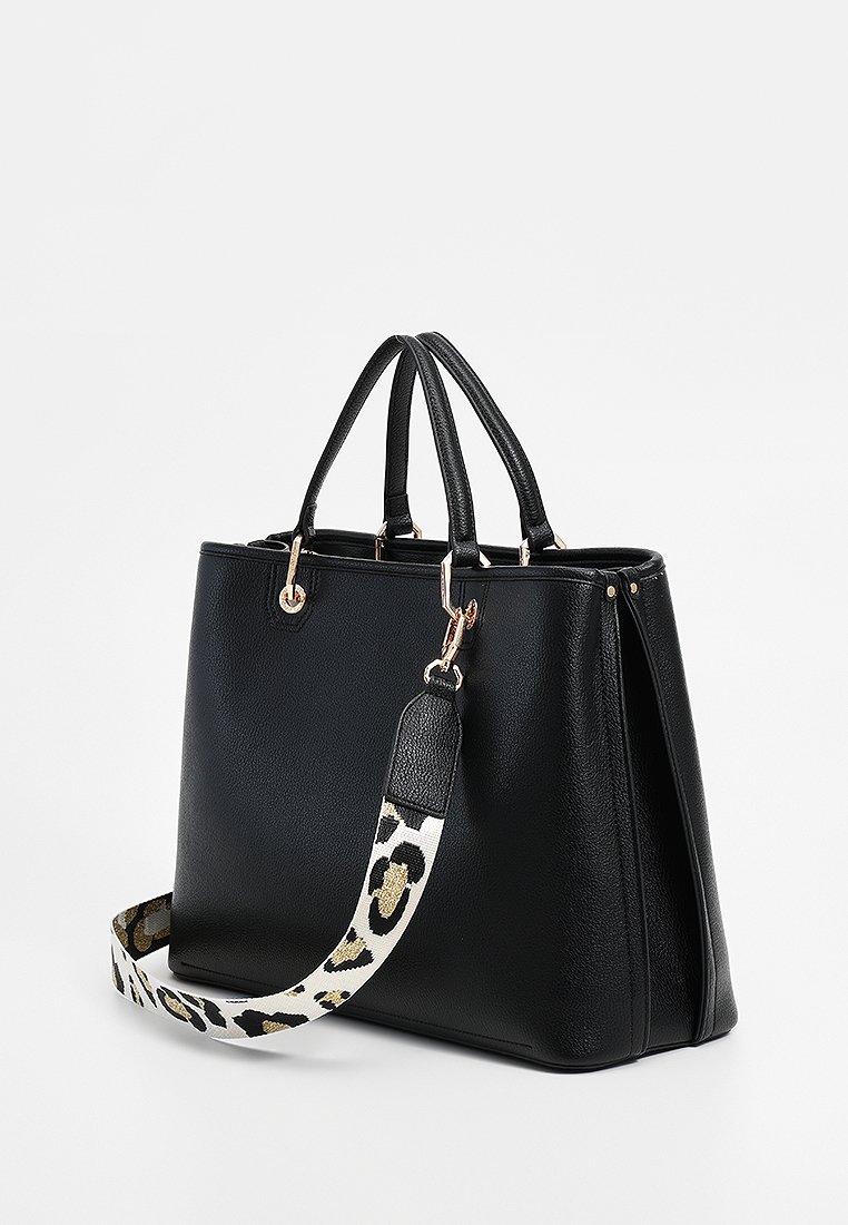 Borsa tote nera in ecopelle con doppi manici superiori, una tracolla rimovibile con motivo e accessori in tonalità oro. Presenta un design strutturato.