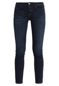 Mörkblå skinny jeans med framknapp och dragkedja, fem fickor och subtila urtvättade detaljer på vit bakgrund.